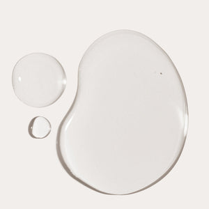 Clear oil droplets of varying sizes on a neutral background representing the smooth texture of You Big Softie Finishing Oil | Crybaby Wax for skincare and body care.