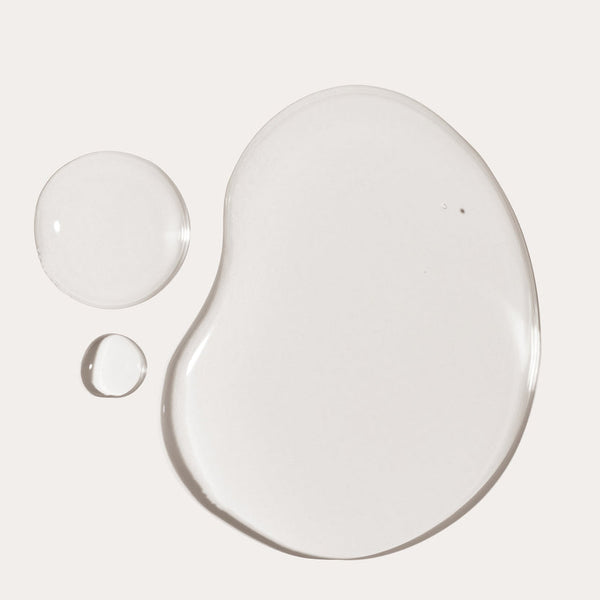 Clear oil droplets of varying sizes on a neutral background representing the smooth texture of You Big Softie Finishing Oil | Crybaby Wax for skincare and body care.