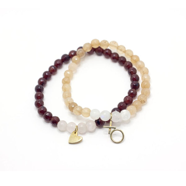 Two beaded bracelets featuring polished gemstones in warm beige and deep burgundy tones with gold heart charm and circular toggle clasp, Gemstone Heart Bracelet | Purpose Jewelry.