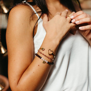 Close-up of a woman wearing the Gemstone Heart Bracelet | Purpose Jewelry, featuring delicate gemstone beads and a gold heart charm on her wrist.
