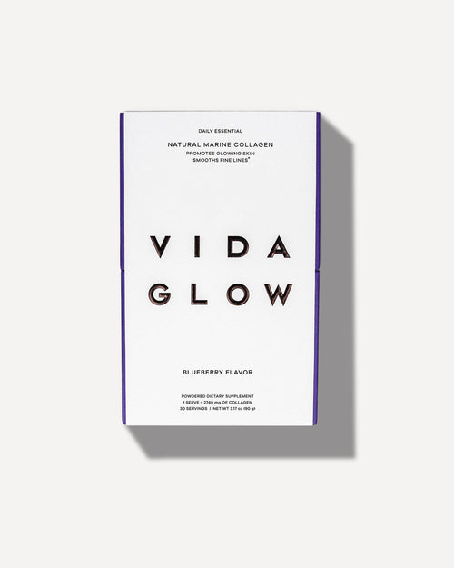 White and purple packaging of Natural Marine Collagen | VIDA GLOW dietary supplement with blueberry flavor promoting glowing skin and smoothing fine lines.