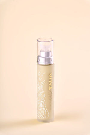 Clear pump bottle of Luminosity Refining Radiance Exfoliator | VOYA with gold lettering and subtle white design on a soft beige background, skincare product for radiance.