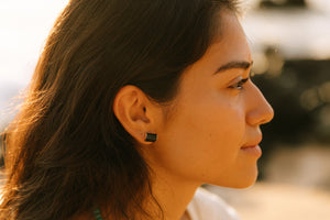 Close-up profile of a woman wearing Black Tourmaline Earrings | Meghan Bo Designs, showcasing the natural black stone studs against her skin in warm sunlight.