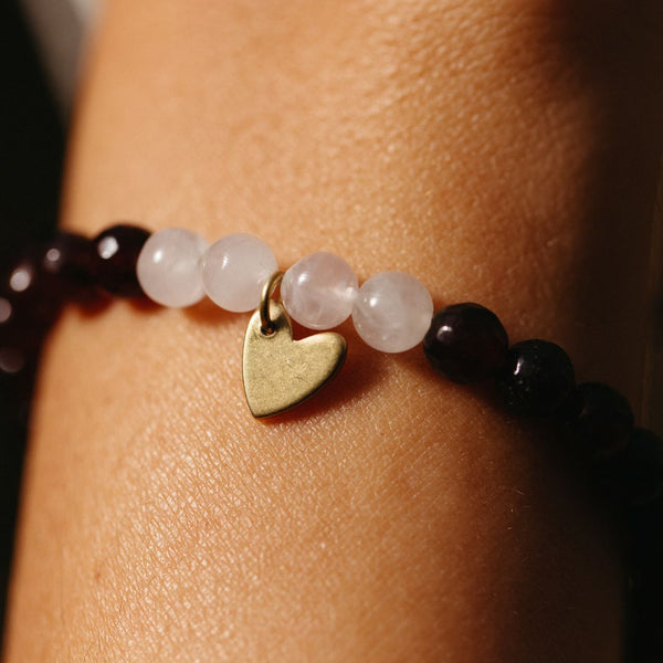 Close-up of a wrist wearing a Gemstone Heart Bracelet | Purpose Jewelry featuring polished round beads and a small gold heart charm.