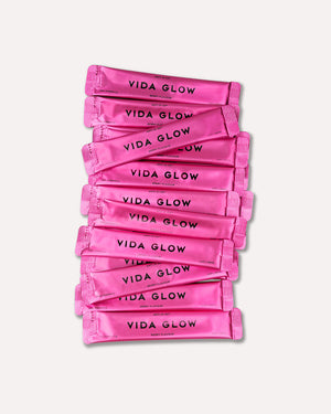 Stack of bright pink sachets labeled with "VIDA GLOW" containing Anti-G-Ox Berry | VIDA GLOW wellness supplements for skincare and body care.