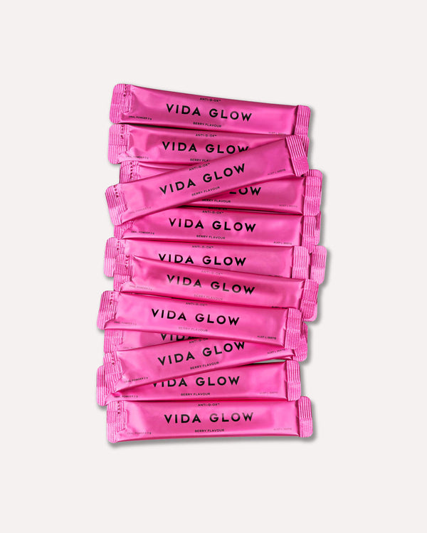 Stack of bright pink sachets labeled with "VIDA GLOW" containing Anti-G-Ox Berry | VIDA GLOW wellness supplements for skincare and body care.