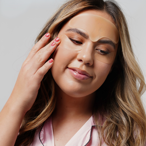 Woman gently touching her face while wearing a translucent Skin Plumping Reusable Forehead Pad | Dreambox Beauty, showcasing skincare and wellness for smooth, plumped skin.