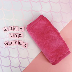 Pink microfiber Cleansing Mitt [Double Cleansing Tool] | Dreambox Beauty placed on a pastel patterned surface next to letter tiles spelling "JUST ADD WATER" for skincare cleansing.