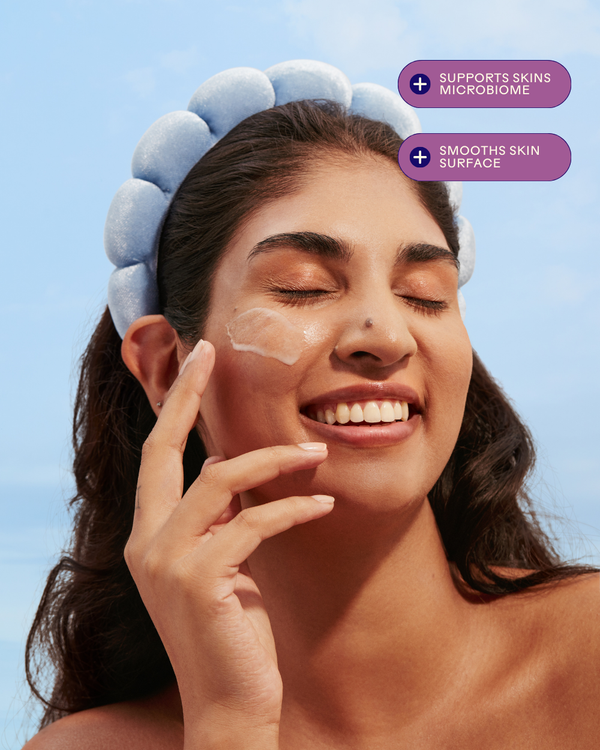 Woman with a blue headband smiling while applying Harmony Cucumber + Kombucha Microbiome Milky Balancing Cleanser | Three Ships on her cheek, highlighting skincare benefits for smoothing skin and supporting the microbiome.