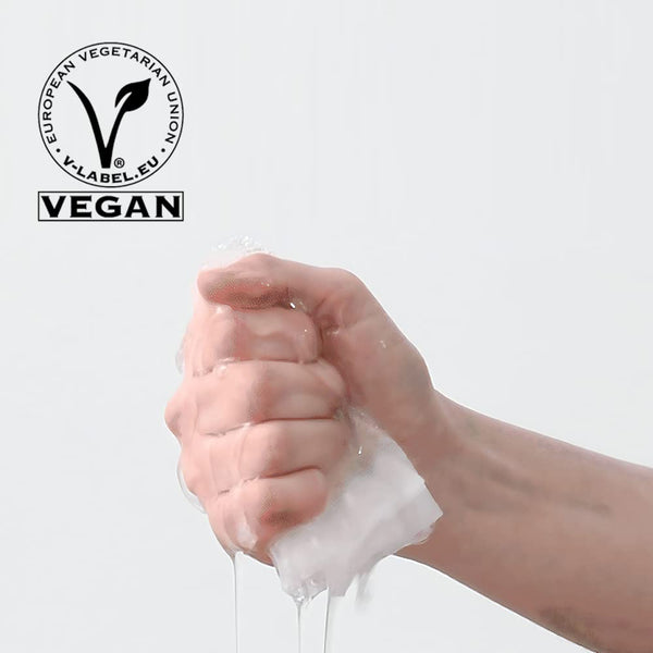 Hand squeezing a wet cotton pad with water dripping, accompanied by a vegan certification logo, representing ImPHYTO AHA | Leaders skincare product.