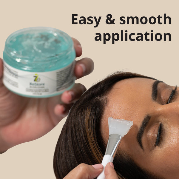 Close-up of a person applying clear gel smoothly on their forehead with a brush, alongside a jar of ReStore Conductive Gel with Bio-Active Complex | 7e Wellness, promoting easy application for skincare and wellness routines.