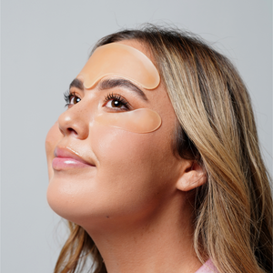Woman wearing translucent skincare pads on forehead and under eyes, demonstrating use of Skin Plumping Reusable Forehead Pad | Dreambox Beauty for glowing, refreshed skin.