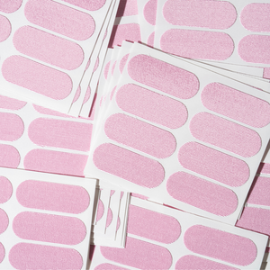 Sheets of pink adhesive strips laid out flat, showcasing multiple rounded rectangular patches for skin application, featuring Face Tape | Dreambox Beauty.