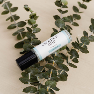 Breathe Rollerball - Respiratory Support | Essence One placed on green eucalyptus leaves, showcasing a wellness supplement for respiratory care and relaxation.
