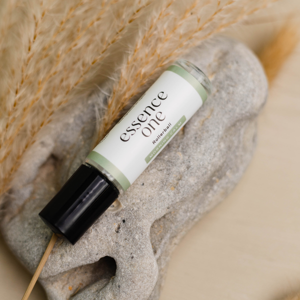 Morning Calm Rollerball - Anxiety Support | Essence One in a clear glass bottle with black cap resting on a textured stone surrounded by dried pampas grass, promoting wellness and skincare.