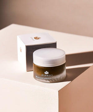 Jar of Microcrystal Exfoliator | Shankara with white lid placed next to its packaging box on a beige surface, showcasing a skincare exfoliation treatment product.