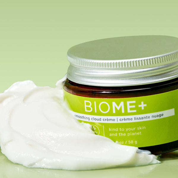 BIOME+ smoothing cloud crème | IMAGE Skincare in a green jar with white cream spread beside it on a light green background, highlighting skincare and wellness.