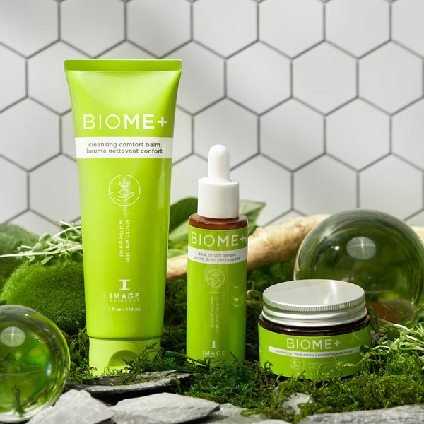 Green skincare products from the BIOME+ smoothing cloud crème | IMAGE Skincare line displayed on moss and natural elements, highlighting wellness and body care.