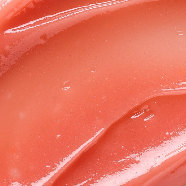 Close-up of glossy, smooth coral-toned balm texture highlighting hydration and softness, representing Hydramemory Plumping Lip Balm | [ comfort zone ] skincare product.