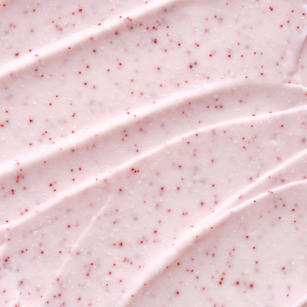 Close-up texture of a creamy pink exfoliating lip scrub with small red exfoliating beads, showcasing Hydramemory Exfoliating Lip Scrub | [ comfort zone ] for skincare use.