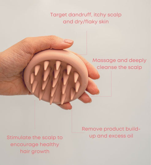 Hand holding a pink scalp scrubber with soft silicone bristles designed to target dandruff, itchy scalp, and dry skin while massaging, cleansing, and stimulating healthy hair growth with the Scalp Scrubber [Revitalizing Scalp Massager] | Dreambox Beauty.