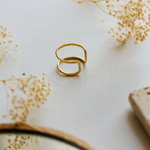 Minimalist gold open band ring displayed on a soft background with delicate dried flowers, showcasing the elegant design of the Chloe Ring | Purpose Jewelry.