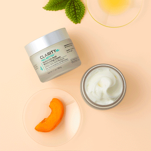 Open jar and closed container of Feel Better™ Hyaluronic Acid Moisturizing Cream | ClarityRx shown with fresh leaf, slice of orange fruit, and bowl of oil on beige background, highlighting skincare and hydration.