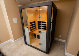 Modern infrared sauna cabin with wooden interior and glass door, designed for relaxation and wellness, featuring heating panels and ambient lighting, HaloSauna™ | Halotherapy Solutions.