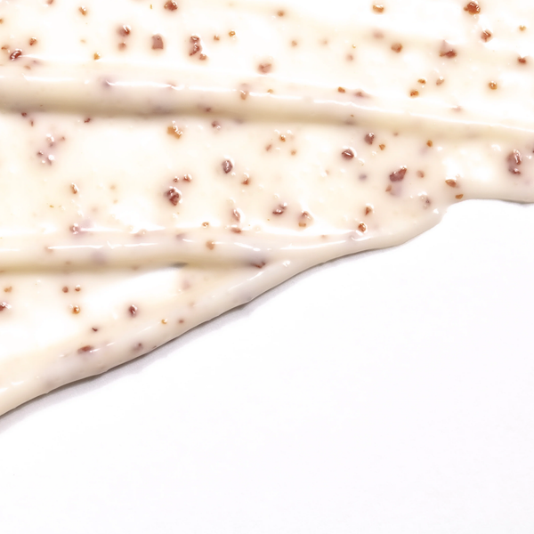 Creamy textured scrub with visible crushed grapeseed particles spread on a white surface, demonstrating the exfoliating quality of Crushed Grapeseed Scrub | Skin Fitness Therapy.