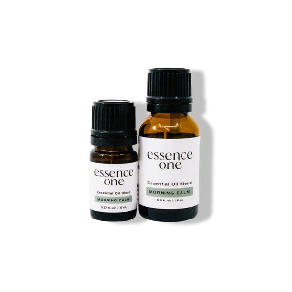 Two amber glass bottles with black caps labeled "essence one" Essential Oil Blends | Essence One, featuring the Morning Calm scent in 5ml and 15ml sizes for wellness and body care.