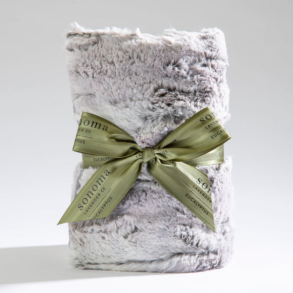 Spa Heat Wrap | Sonoma Lavender wrapped in a soft, plush silver-gray fabric with a green ribbon tied in a bow, designed for soothing body care and wellness recovery.