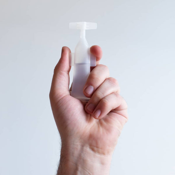 Hand holding a single translucent Activator Capsules 25ct box 12oz/3mL | Force of Nature capsule against a plain light background, showcasing the product's sleek design.