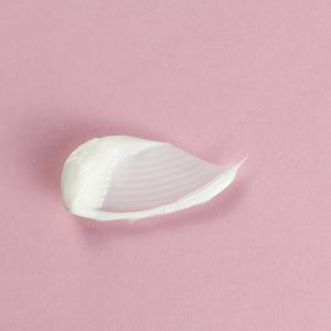 A smooth, creamy texture of Feel Better™ Hyaluronic Acid Moisturizing Cream | ClarityRx on a soft pink background, highlighting its rich skincare formulation.
