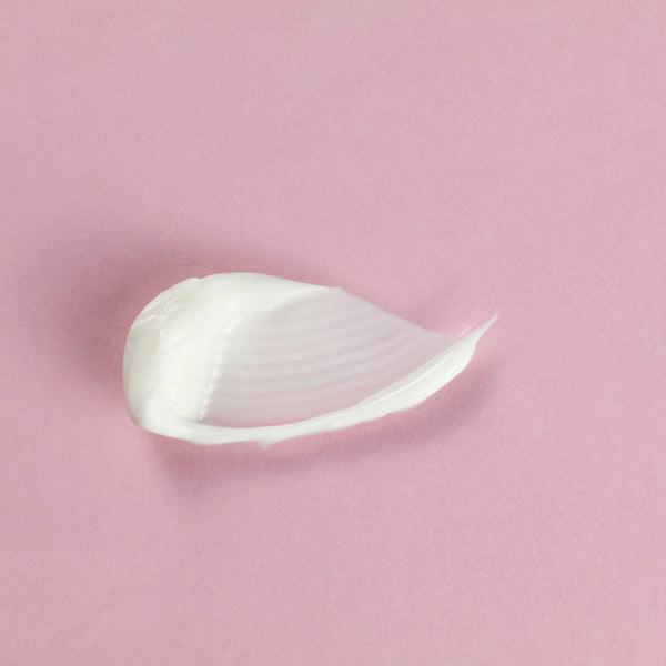 A smooth, creamy texture of Feel Better™ Hyaluronic Acid Moisturizing Cream | ClarityRx on a soft pink background, highlighting its rich skincare formulation.