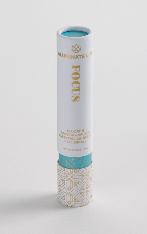 Focus Rollerball | Aluminate Life fluorite crystal-infused essential oil blend in a sleek white and gold container with decorative patterns for skincare and wellness use.