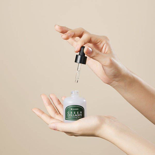 Hands holding a dropper and an open bottle of Green Collagen Firming Serum | Leaders against a neutral background, highlighting skincare and wellness care.
