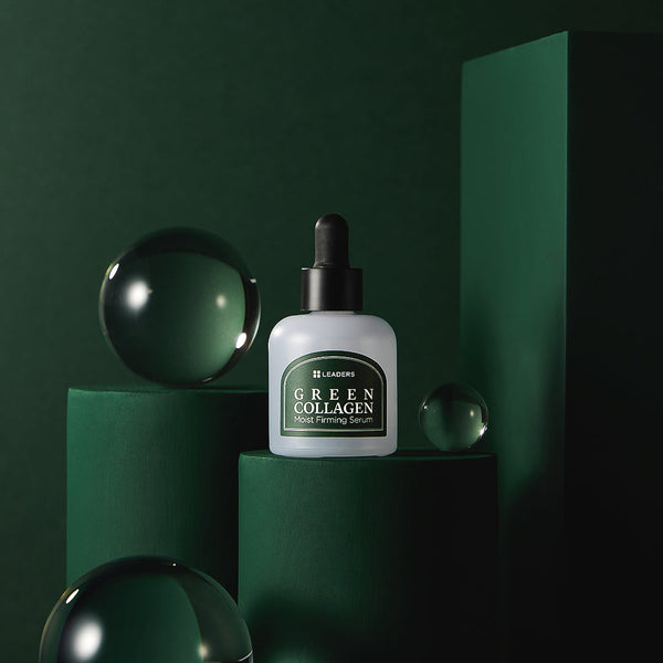 Green Collagen Firming Serum | Leaders bottle with dropper displayed on dark green geometric pedestals surrounded by clear glass spheres, highlighting skincare and wellness supplements.