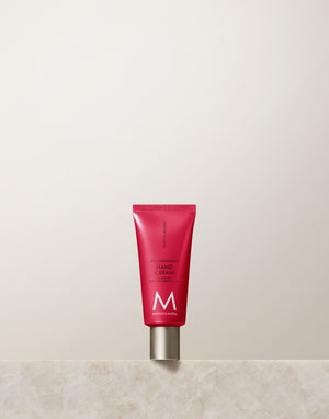 Red tube of Hand Cream | Moroccanoil standing upright on a marble surface against a neutral background, emphasizing skincare and body care products.