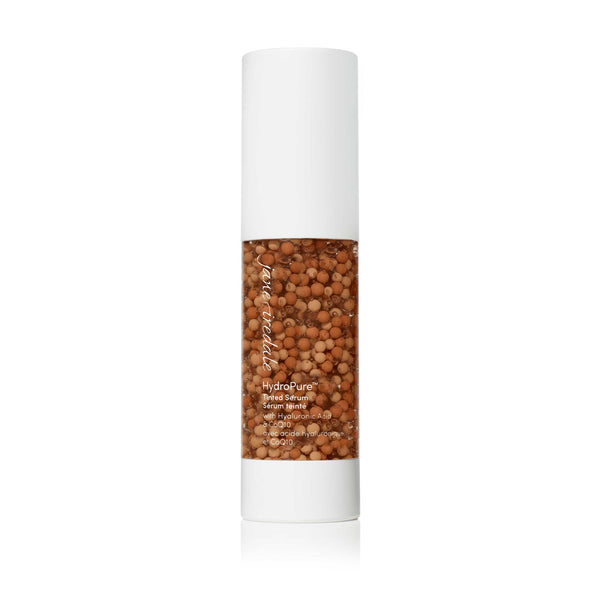 Clear pump bottle of HydroPure™ Tinted Serum with Hyaluronic Acid & CoQ10 | Jane Iredale showing tinted serum with small brown beads inside for skincare and wellness.