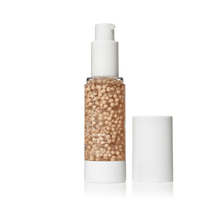 Clear pump bottle of HydroPure™ Tinted Serum with Hyaluronic Acid & CoQ10 | Jane Iredale showing light beige serum beads and white cap next to it, skincare product for hydration and brightening.