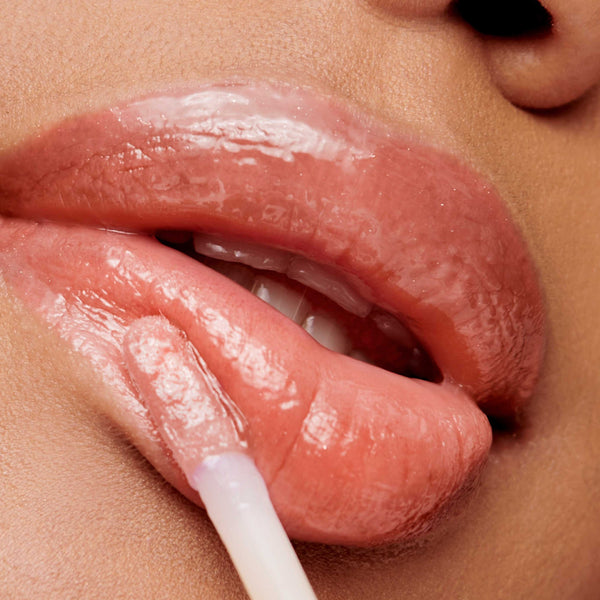 Close-up of lips applying a glossy, natural peach shade using Hydropure Hyaluronic Lip Gloss | Jane Iredale for a smooth, hydrated look.