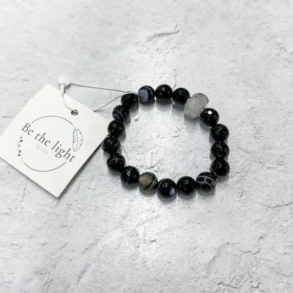 Black Tourmalinated Quartz Luxe Bracelet | Be the Light with polished black and clear beads, displayed on a light textured surface with a branded tag nearby.