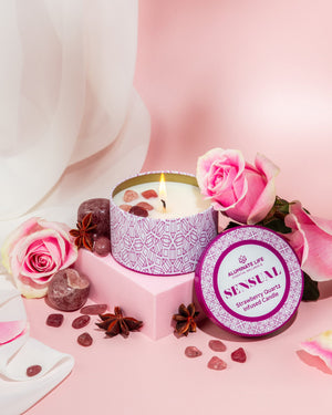 Sensual Candle Tin 6 oz | Aluminate Life featuring a lit candle with strawberry quartz stones, surrounded by pink roses and star anise for a soothing and romantic ambiance.