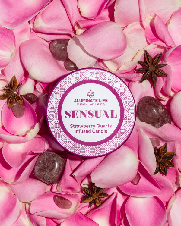 Sensual Candle Tin 6 oz | Aluminate Life surrounded by pink rose petals, strawberry quartz stones, and star anise pods, evoking a calming, wellness-inspired ambiance.