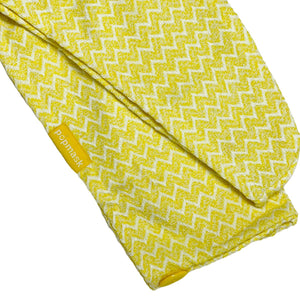 Close-up of a yellow microfiber fabric with a zigzag pattern and a small Popmask label, part of the Microfiber Hair Turban | Popmask for skincare and wellness routines.