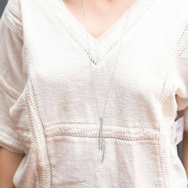 Close-up of a person wearing a delicate silver pendant on a slim chain paired with a textured cream top, showcasing the elegant Kailani Necklace | Purpose Jewelry.