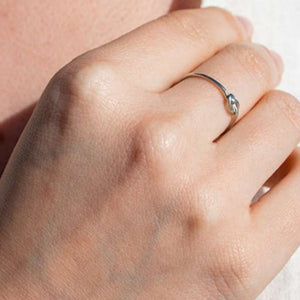 Close-up of a hand wearing a delicate silver Knot Ring | Purpose Jewelry, showcasing its minimalist design and elegant knot detail on the finger.