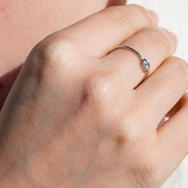 Close-up of a hand wearing a delicate silver Knot Ring | Purpose Jewelry, showcasing its minimalist design and elegant knot detail on the finger.
