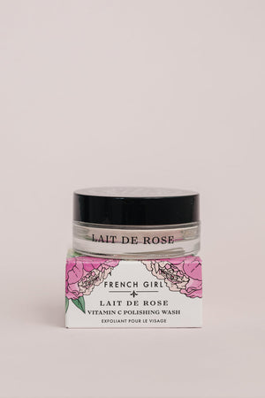 Clear jar with black lid containing Vitamin C Polishing Facial Wash & Mask | French Girl, placed on a white and pink floral box with elegant branding for skincare use.