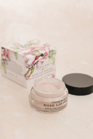 Open jar of Rose LIp Polish | French Girl lip exfoliant next to floral decorative box on light beige surface for skincare and body care wellness routine.